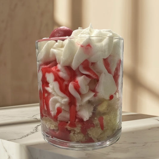 Doodlations Coffee Bar & Boutique Cherry Cheesecake candle in a glass jar, resembling dessert with white cream and red drizzle.
