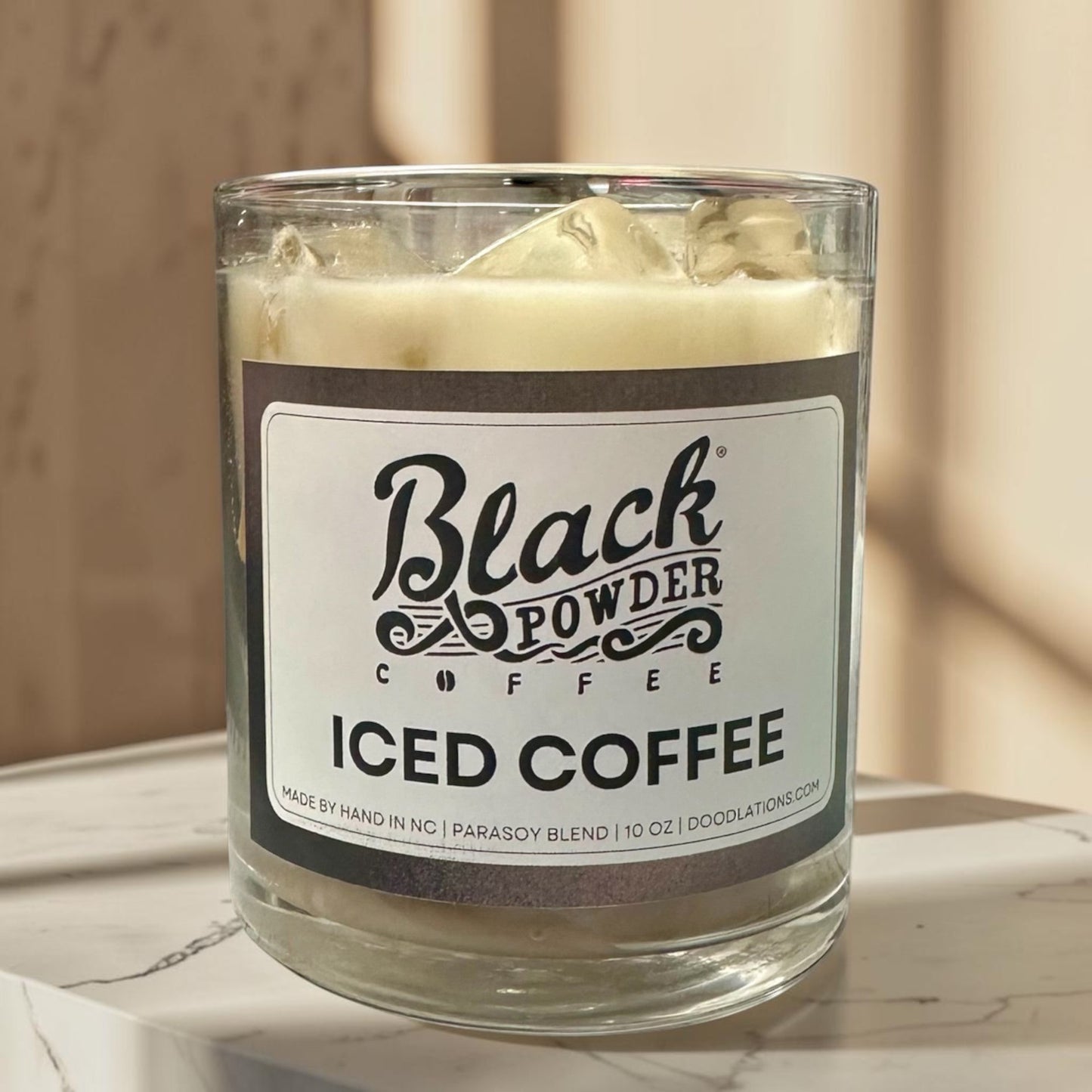 Black Powder Iced Coffee candle in a glass jar with a creamy white wax and faux ice cubes on top.