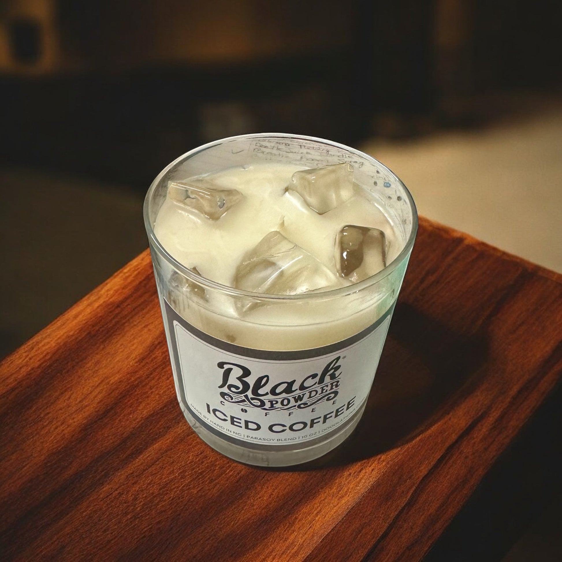 Black Powder Iced Coffee candle in a glass jar with a creamy white wax and faux ice cubes on top.