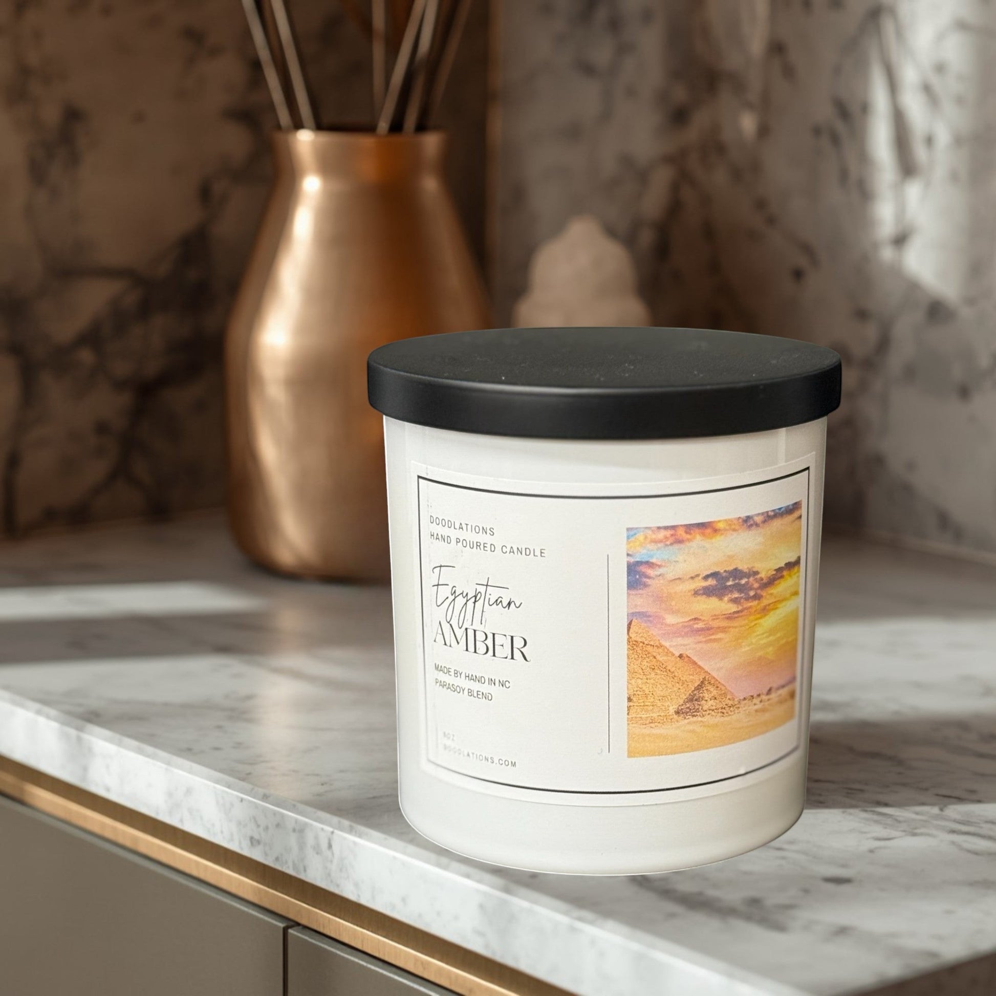 Egyptian Amber hand-poured soy blend candle in a white jar with a black lid.