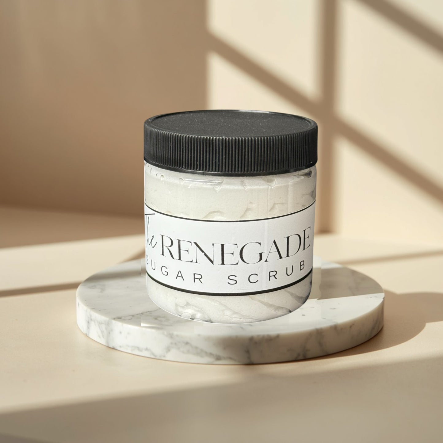 The Renegade Men's Sugar Scrub in a clear jar with a black lid. White textured scrub inside.