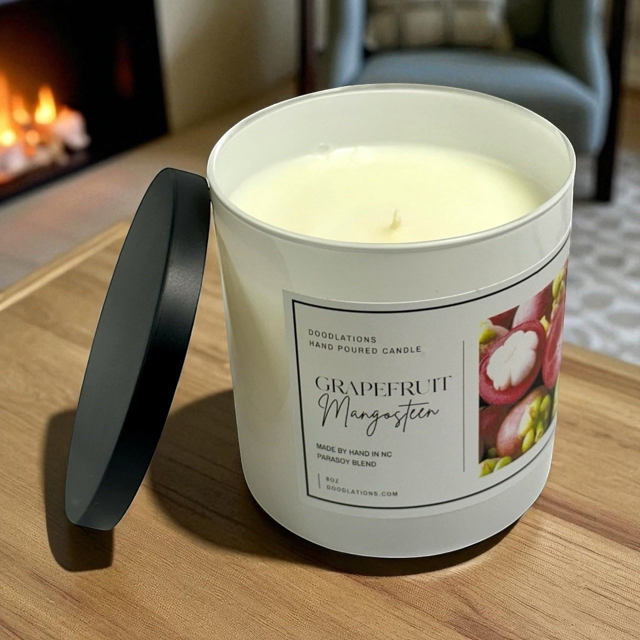 Grapefruit & Mangosteen hand-poured candle in a white jar with a black lid. Features a label with fruit imagery.
