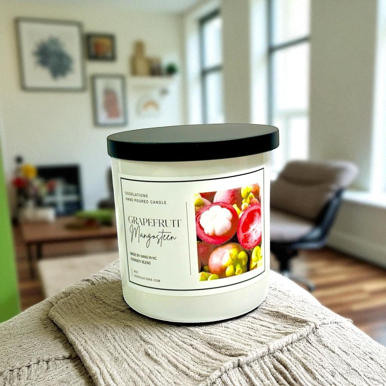 Grapefruit & Mangosteen hand-poured candle in a white jar with a black lid. Features a label with fruit imagery.