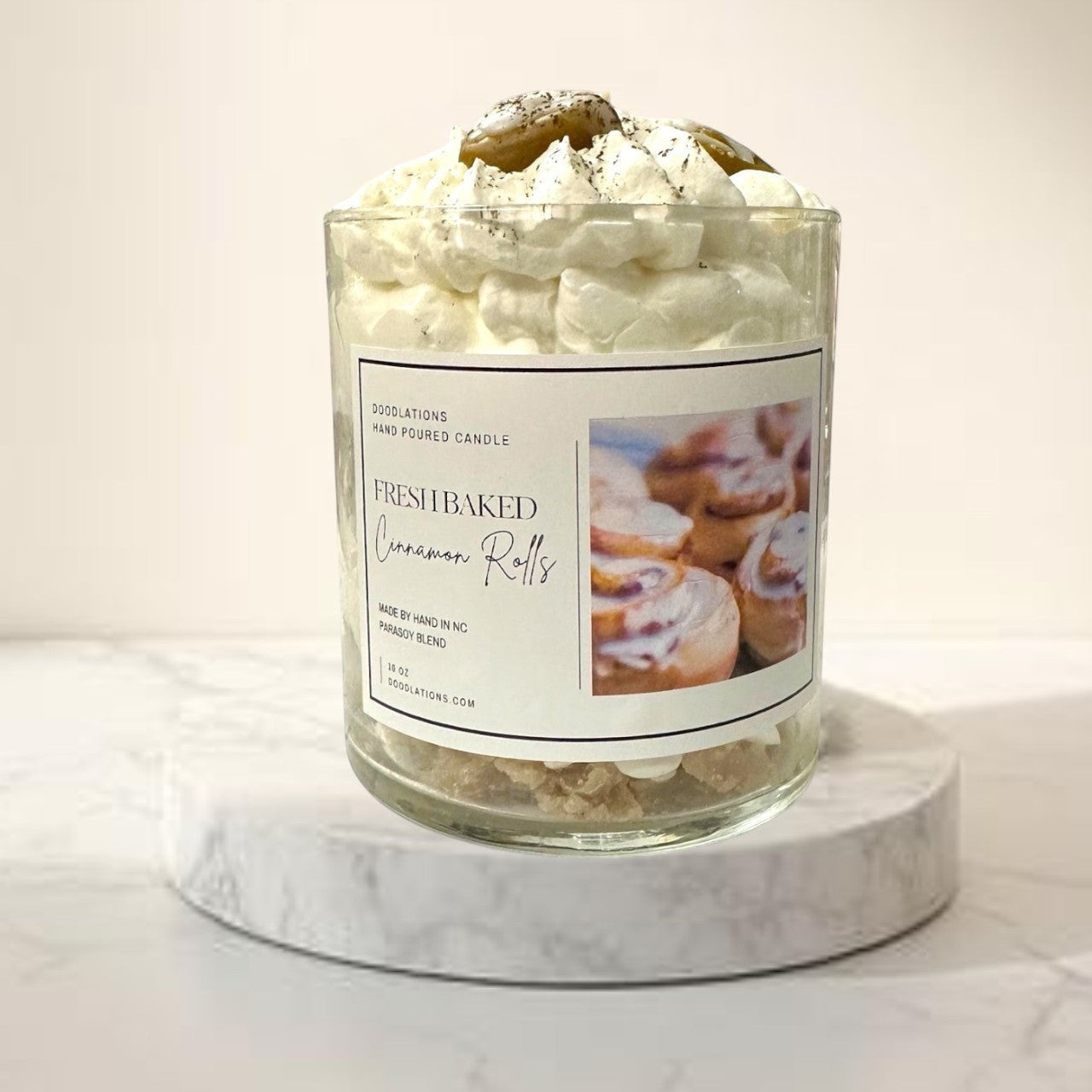 Doodlations Coffee Bar & Boutique Cinnamon Bun candle with decorative wax toppings resembling cinnamon rolls and whipped cream.