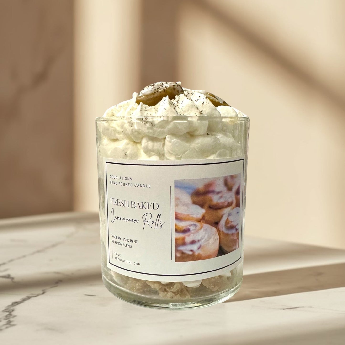 Doodlations Coffee Bar & Boutique Cinnamon Bun candle with decorative wax toppings resembling cinnamon rolls and whipped cream.