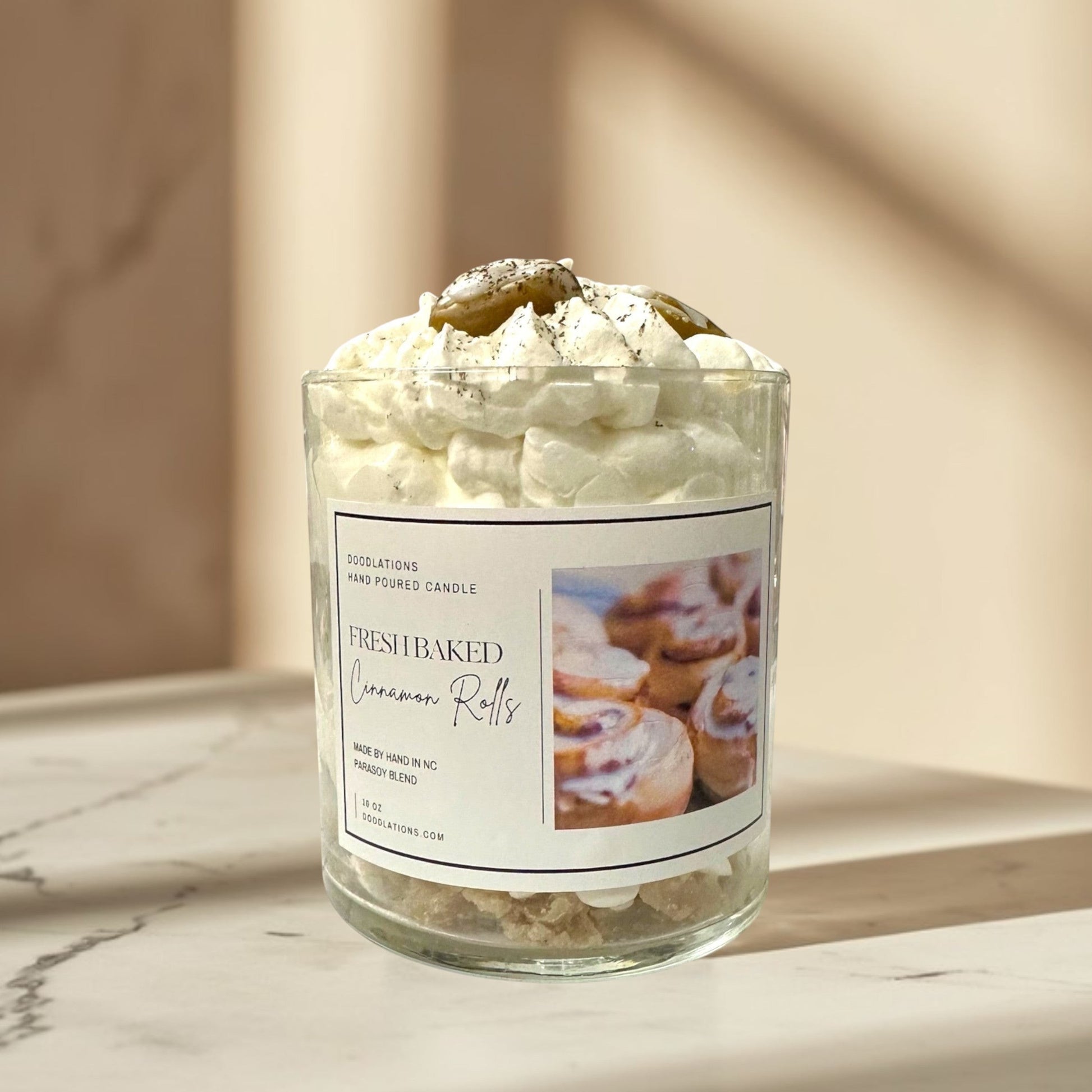 Doodlations Coffee Bar & Boutique Cinnamon Bun candle with decorative wax toppings resembling cinnamon rolls and whipped cream.