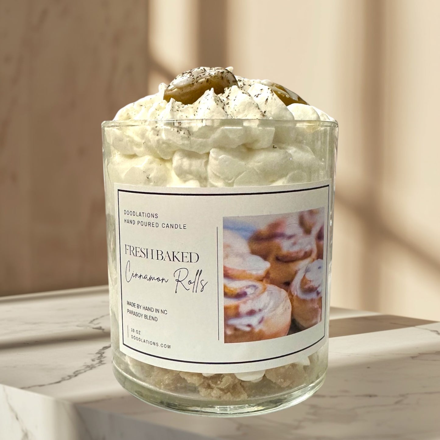 Doodlations Coffee Bar & Boutique Cinnamon Bun candle with decorative wax toppings resembling cinnamon rolls and whipped cream.