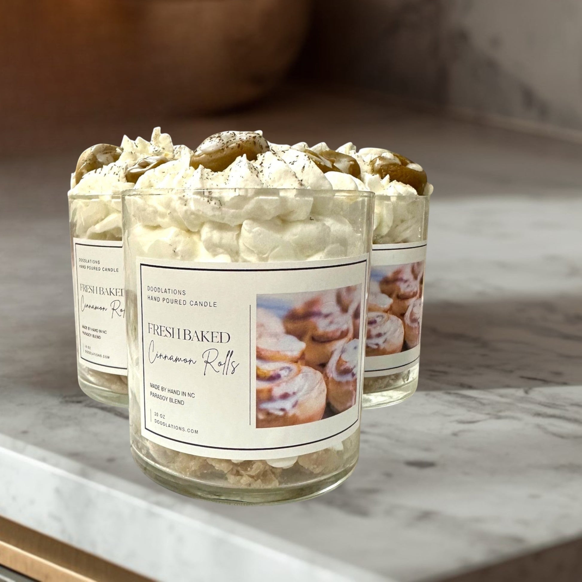 Doodlations Coffee Bar & Boutique Cinnamon Bun candle with decorative wax toppings resembling cinnamon rolls and whipped cream.