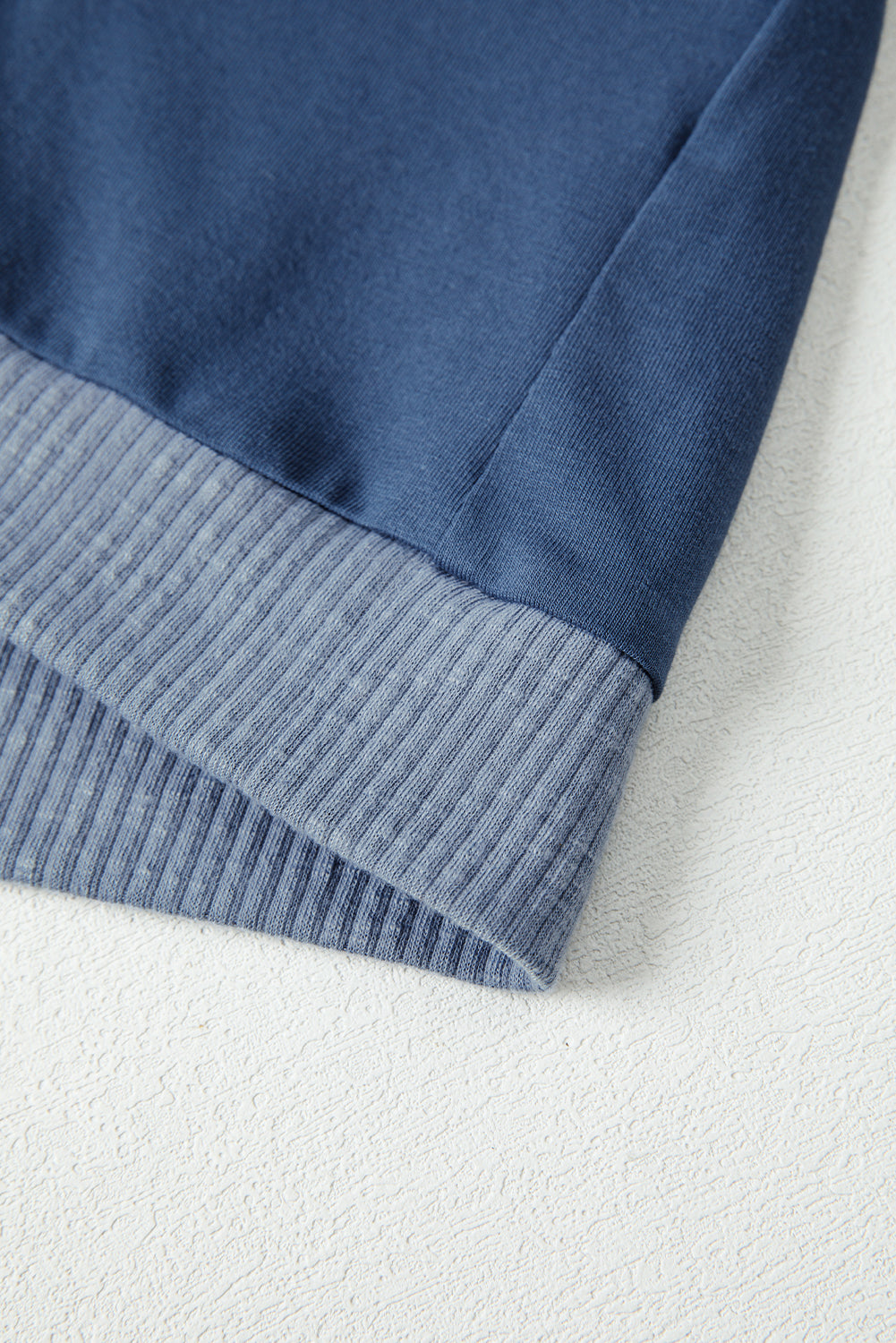Close-up of a blue fabric edge on a textured white background