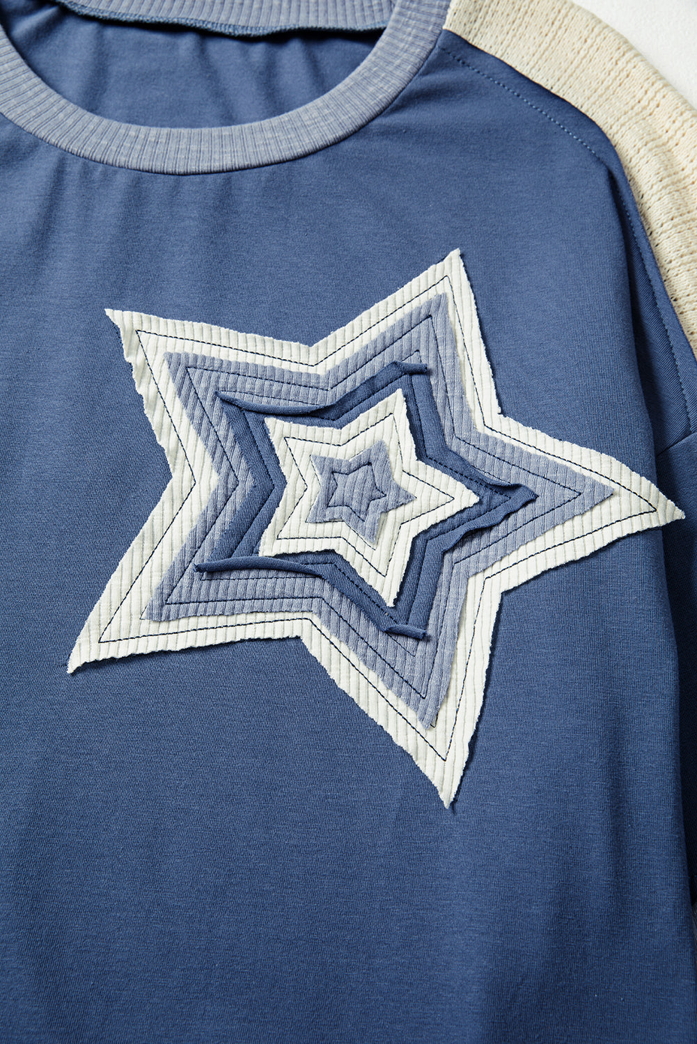 Blue shirt with a star-shaped patch on a plain background