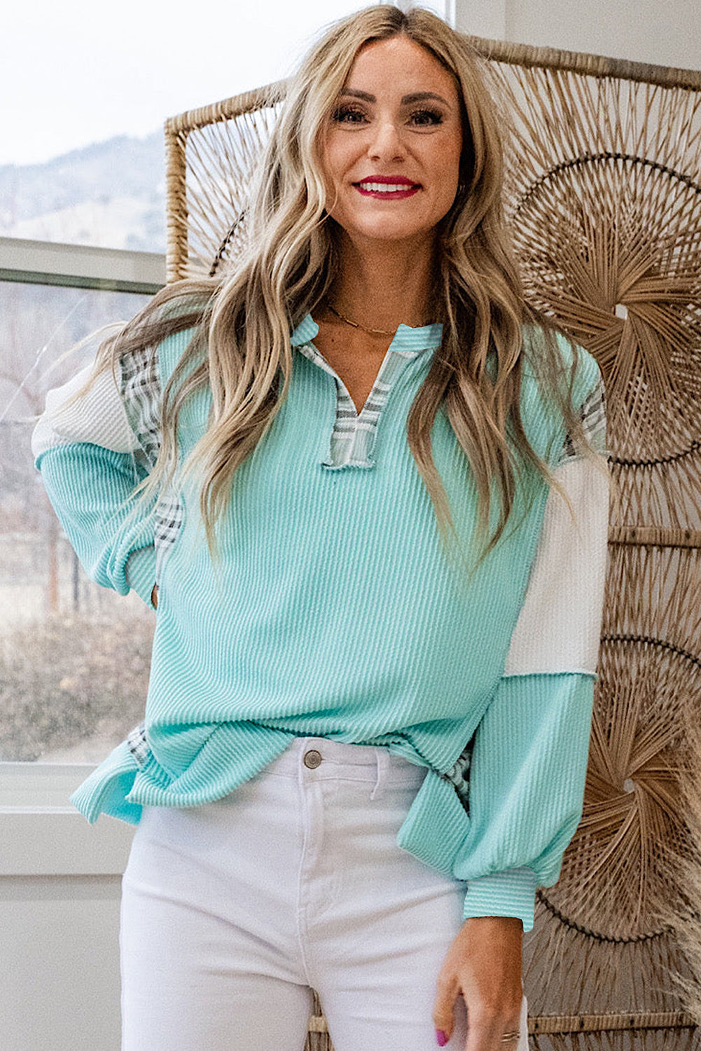 Woman wearing a light blue and white top with a blurred outdoor background