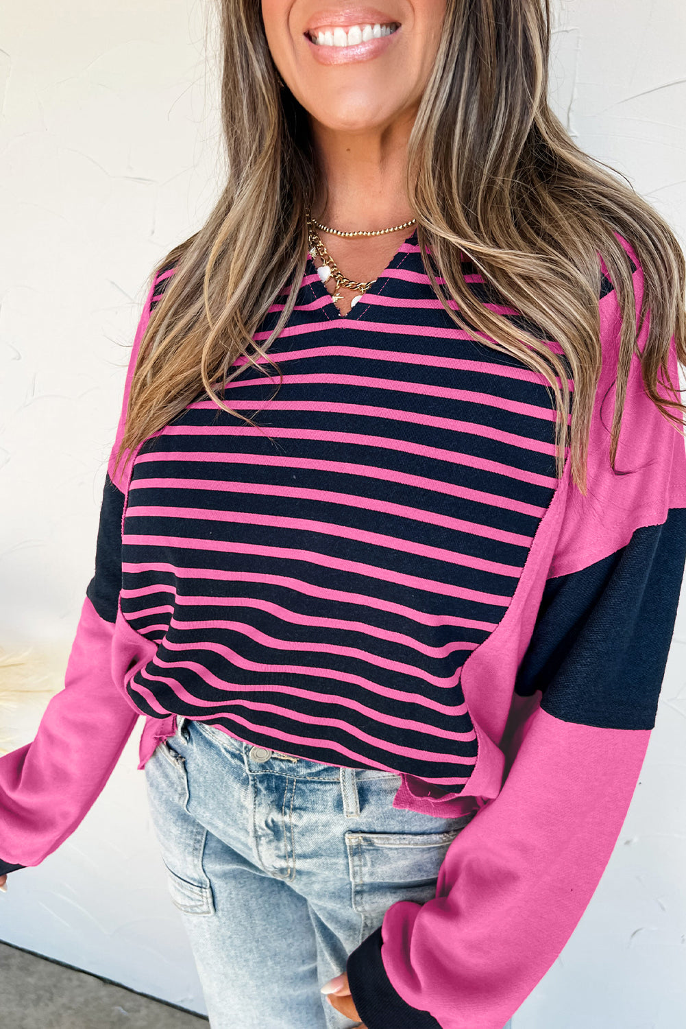 Woman wearing a pink and black striped shirt with a matching cardigan.