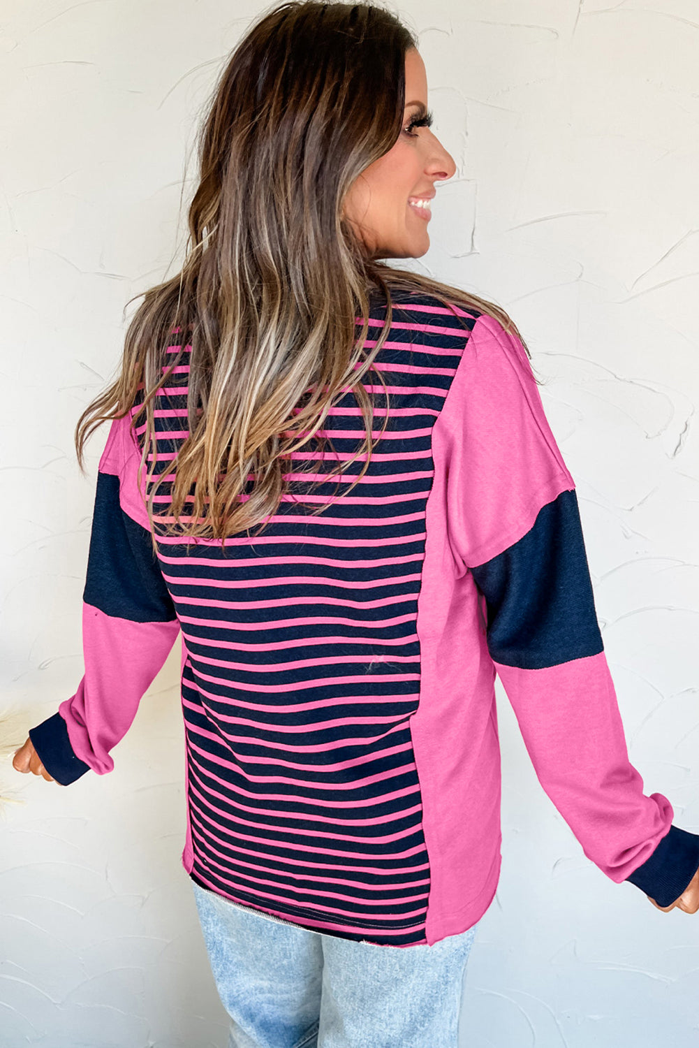 Woman wearing a pink and navy striped long-sleeve top against a white background