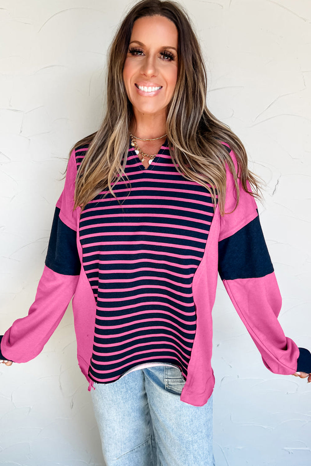 Woman wearing a pink and navy striped long-sleeve top against a white background