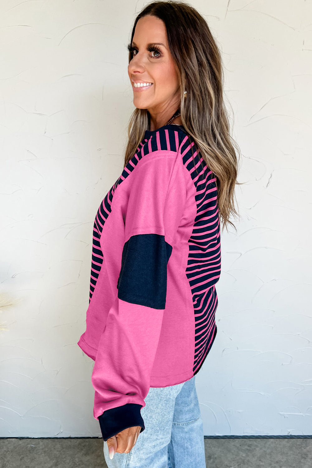 Woman wearing a pink and navy striped jacket against a white wall