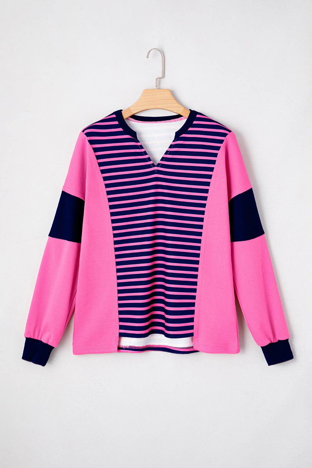 Pink and navy striped shirt on a hanger against a white background