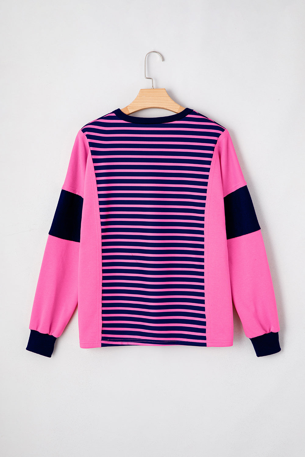 Pink and navy striped sweater on a hanger against a white background