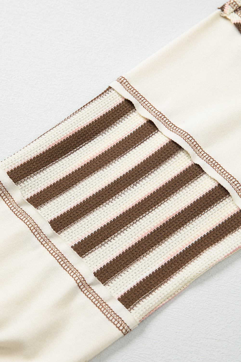 Striped pouch with brown and beige pattern on a light gray background