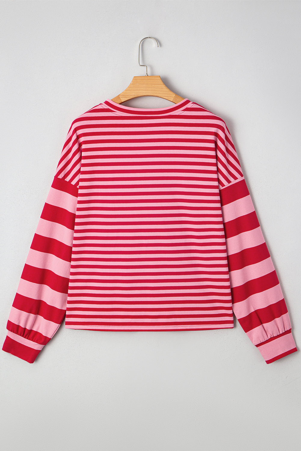 Red and pink striped long-sleeve shirt on a hanger against a white background