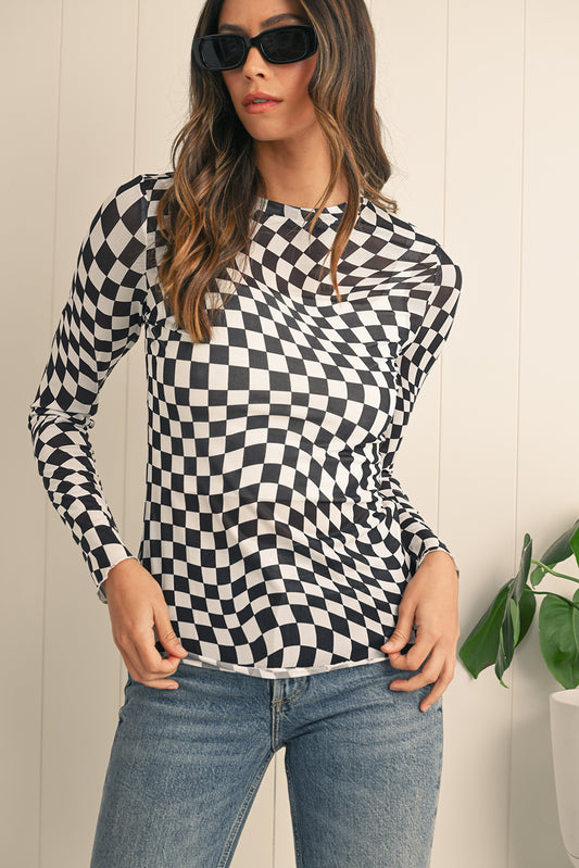 Woman wearing a black and white checkered long-sleeve top and blue jeans against a light background.