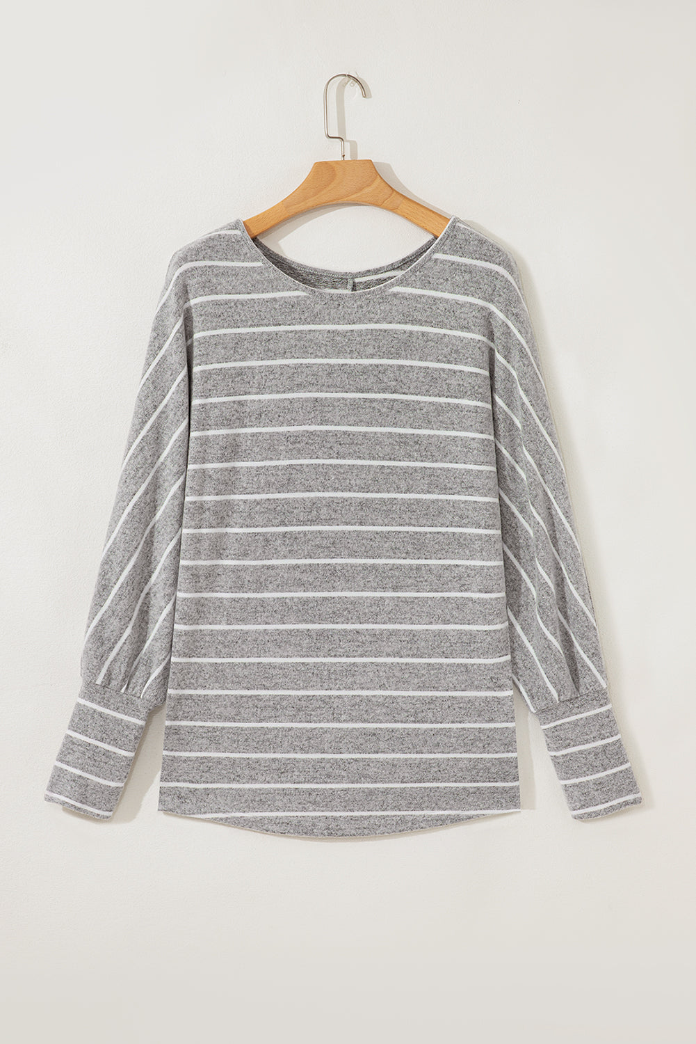 Gray and white striped sweater on a wooden hanger against a white background