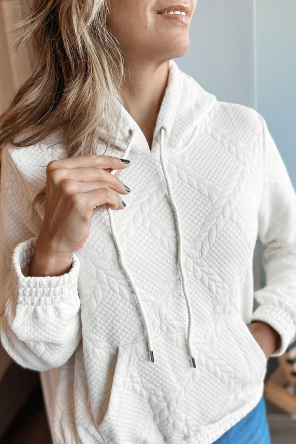 Woman wearing a white textured jacket with a blurred background
