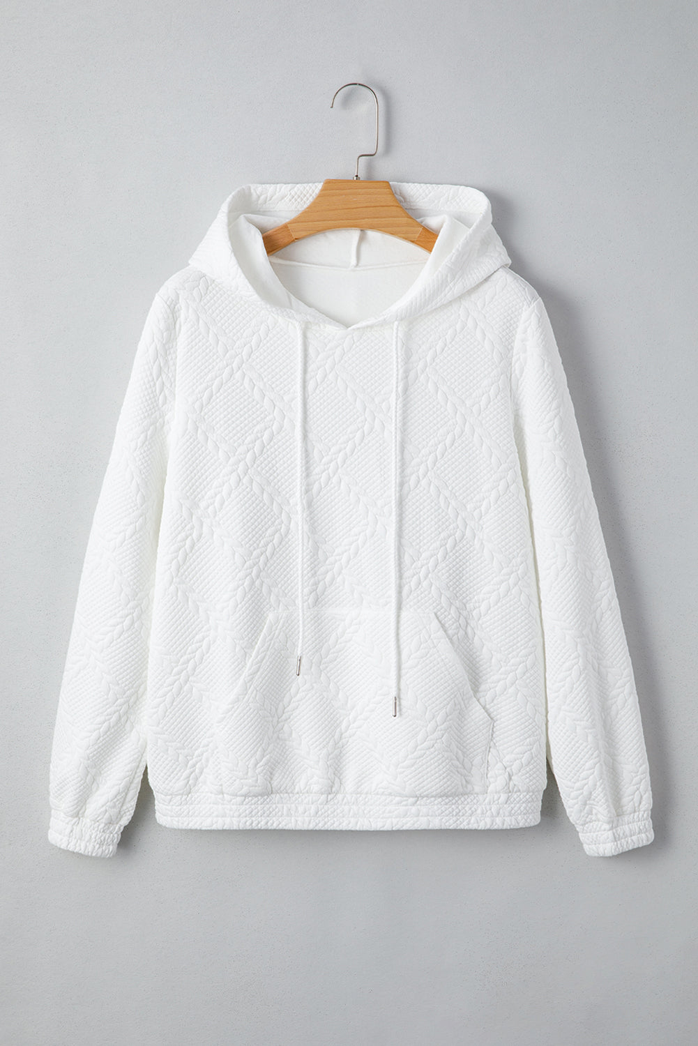 White textured hoodie on a wooden hanger against a gray background
