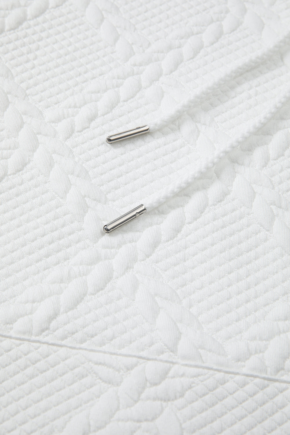 Close-up of a textured white fabric surface with two metallic objects.