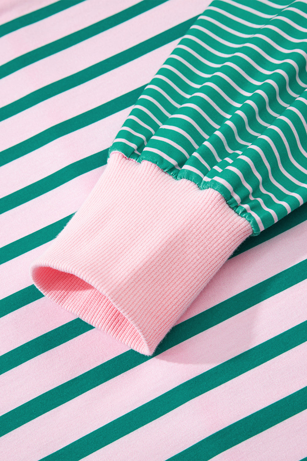 Green and white striped fabric with pink trim on a striped background