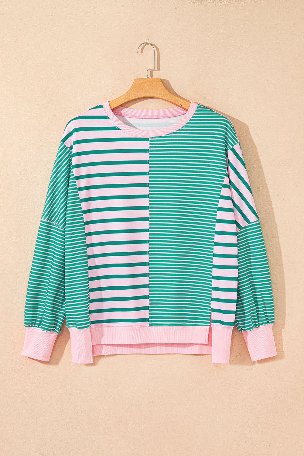 Green and white striped sweater with pink accents on a beige background