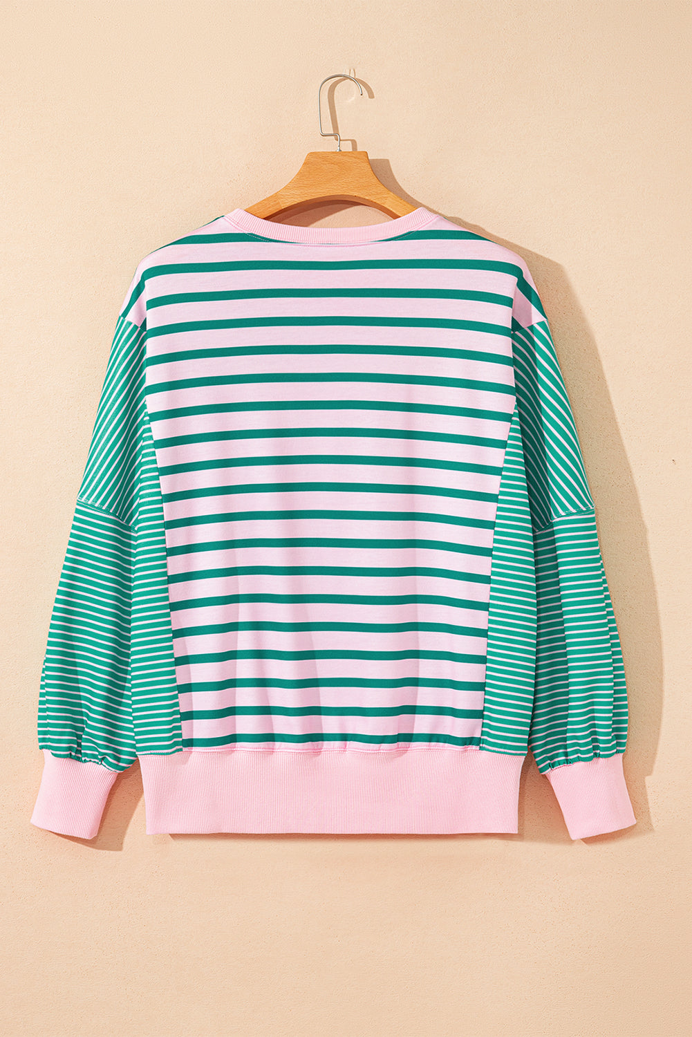 Striped sweater with green and white horizontal stripes on a beige background