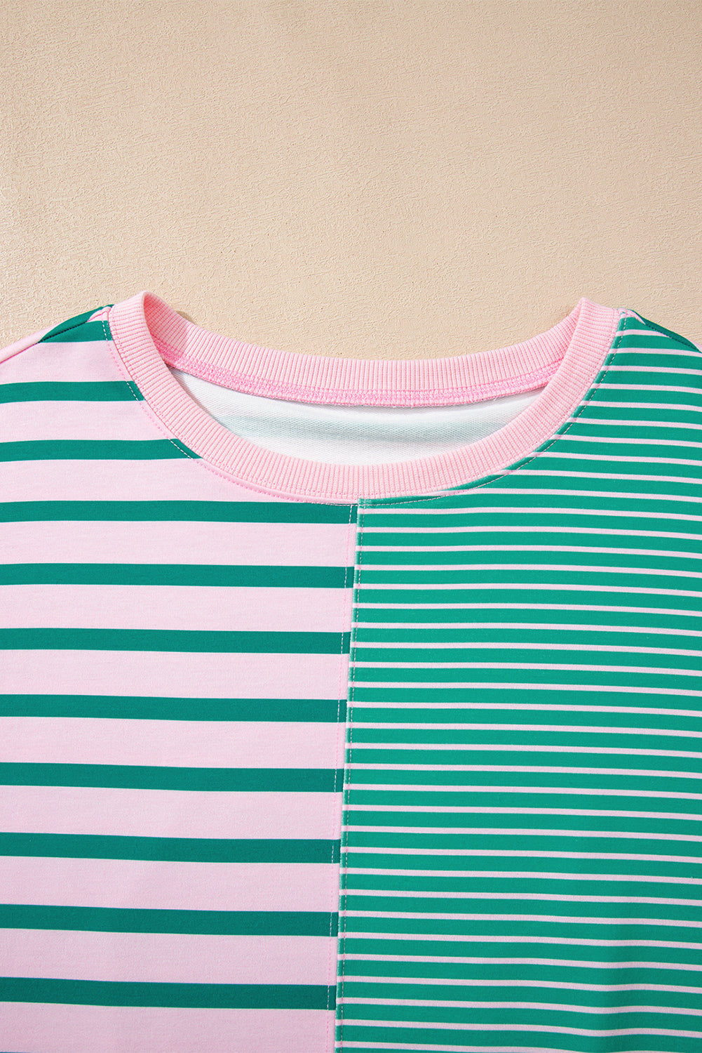 Close-up of a striped shirt with pink and green horizontal stripes on a beige background
