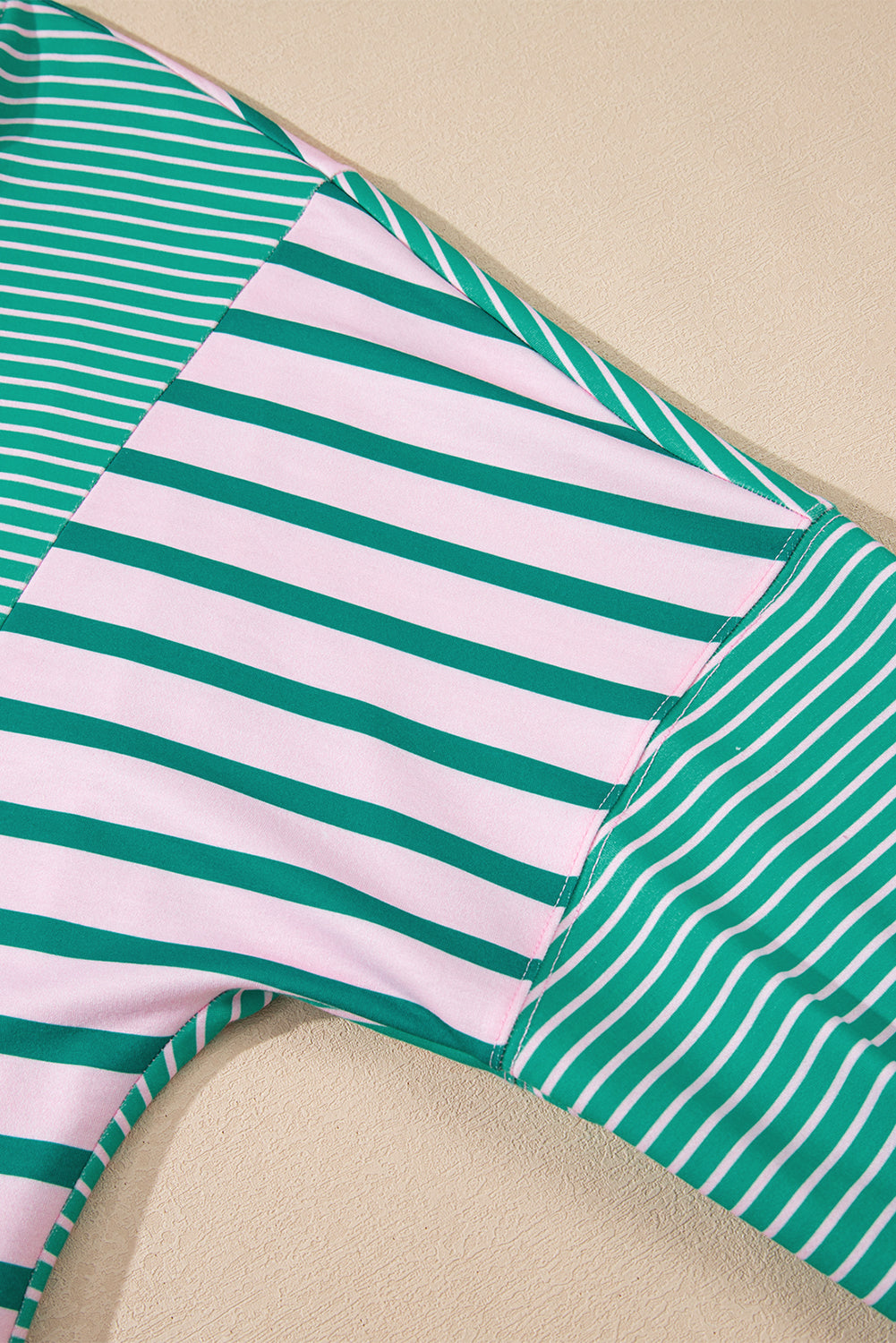 Green and pink striped fabric on a beige background