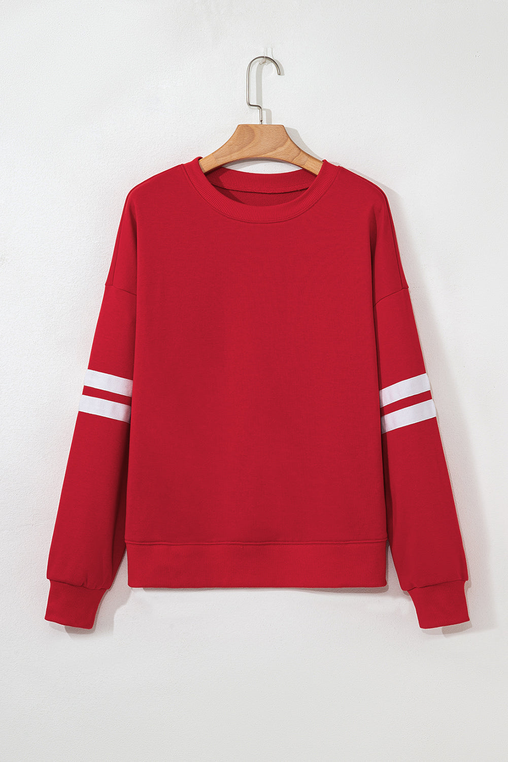 Red sweatshirt with white stripes on sleeves on a hanger against a white background
