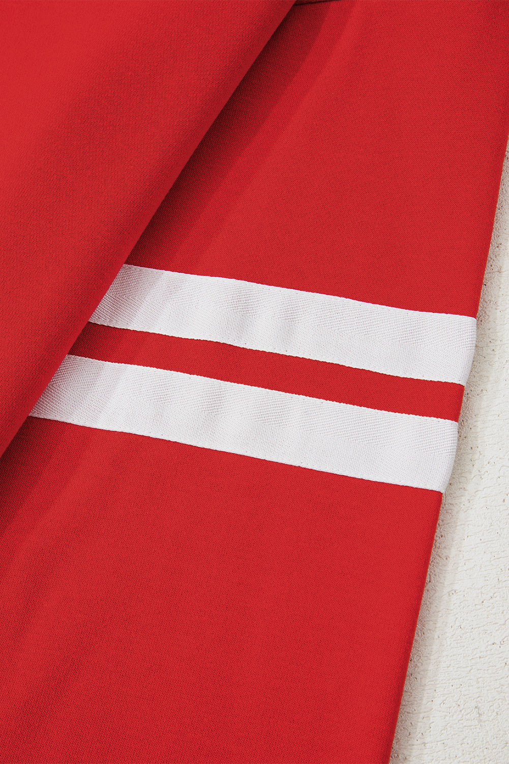 Close-up of red fabric with white reflective stripes on a textured surface