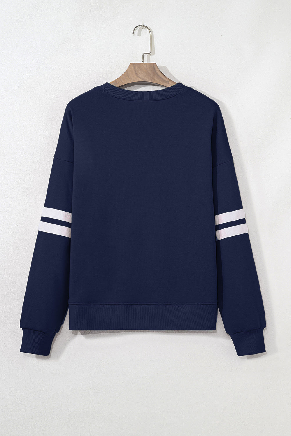 Navy blue sweatshirt with white stripes on sleeves on a hanger against a white background