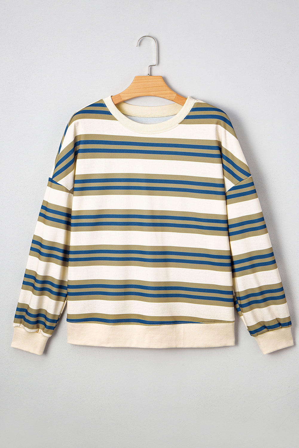 Striped sweater on a hanger against a gray background