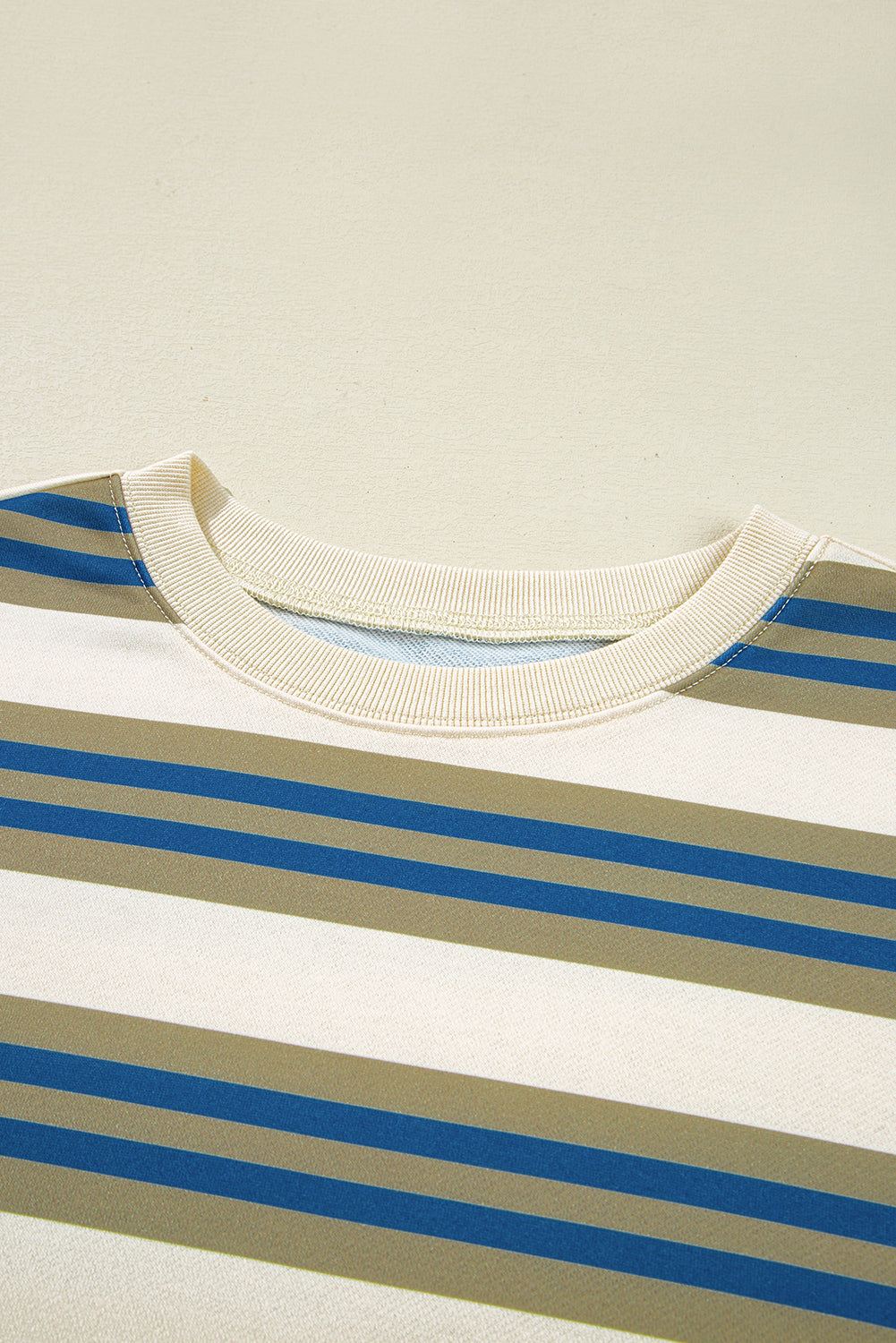 Close-up of a striped shirt with blue and beige horizontal lines on a light background