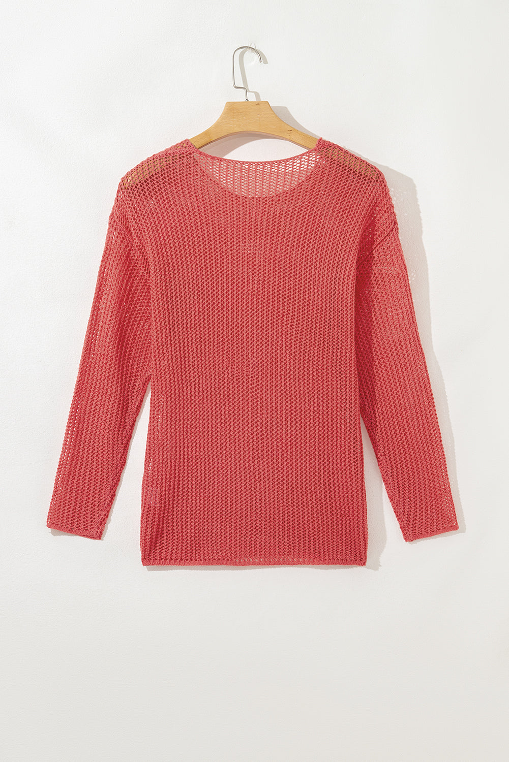 Red knitted sweater on a hanger against a white background