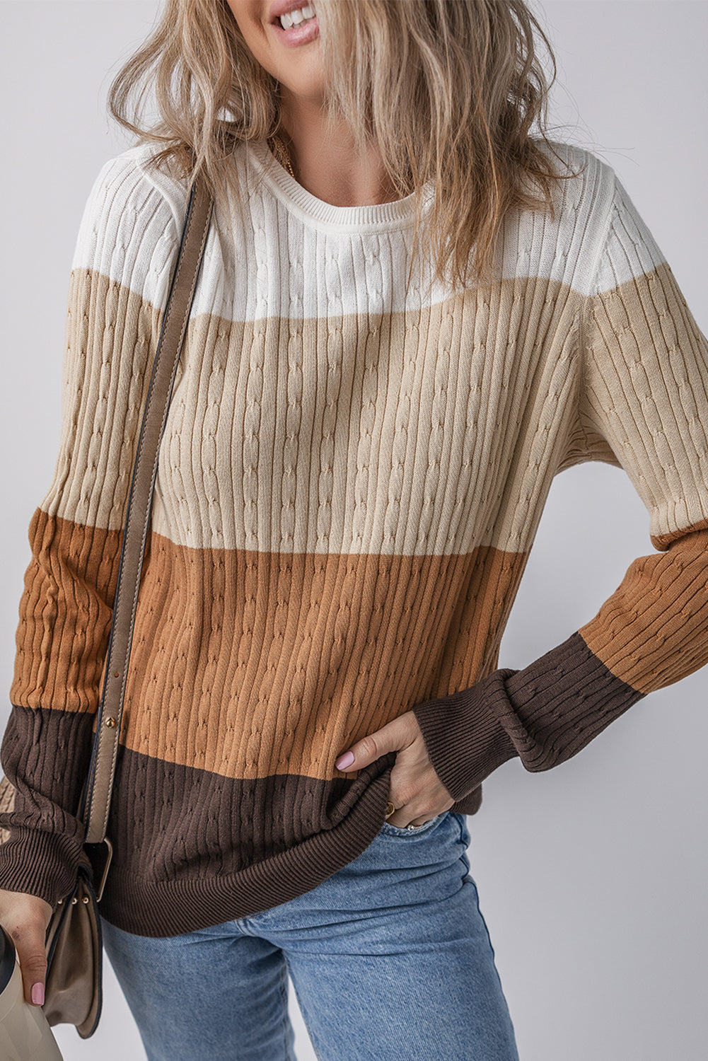 Person wearing a striped sweater with a neutral color palette on a plain background