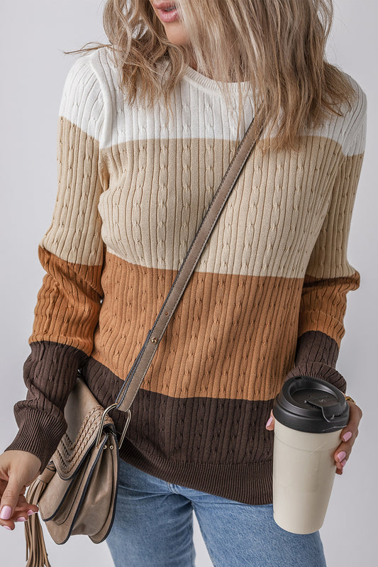 Person wearing a striped sweater holding a coffee cup and a bag against a plain background