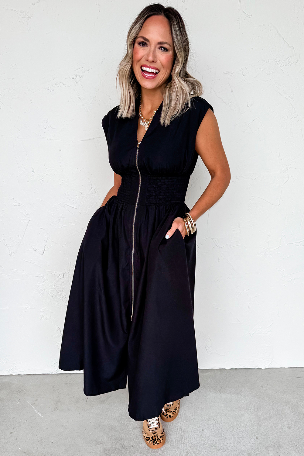 Woman wearing a black sleeveless dress against a white background