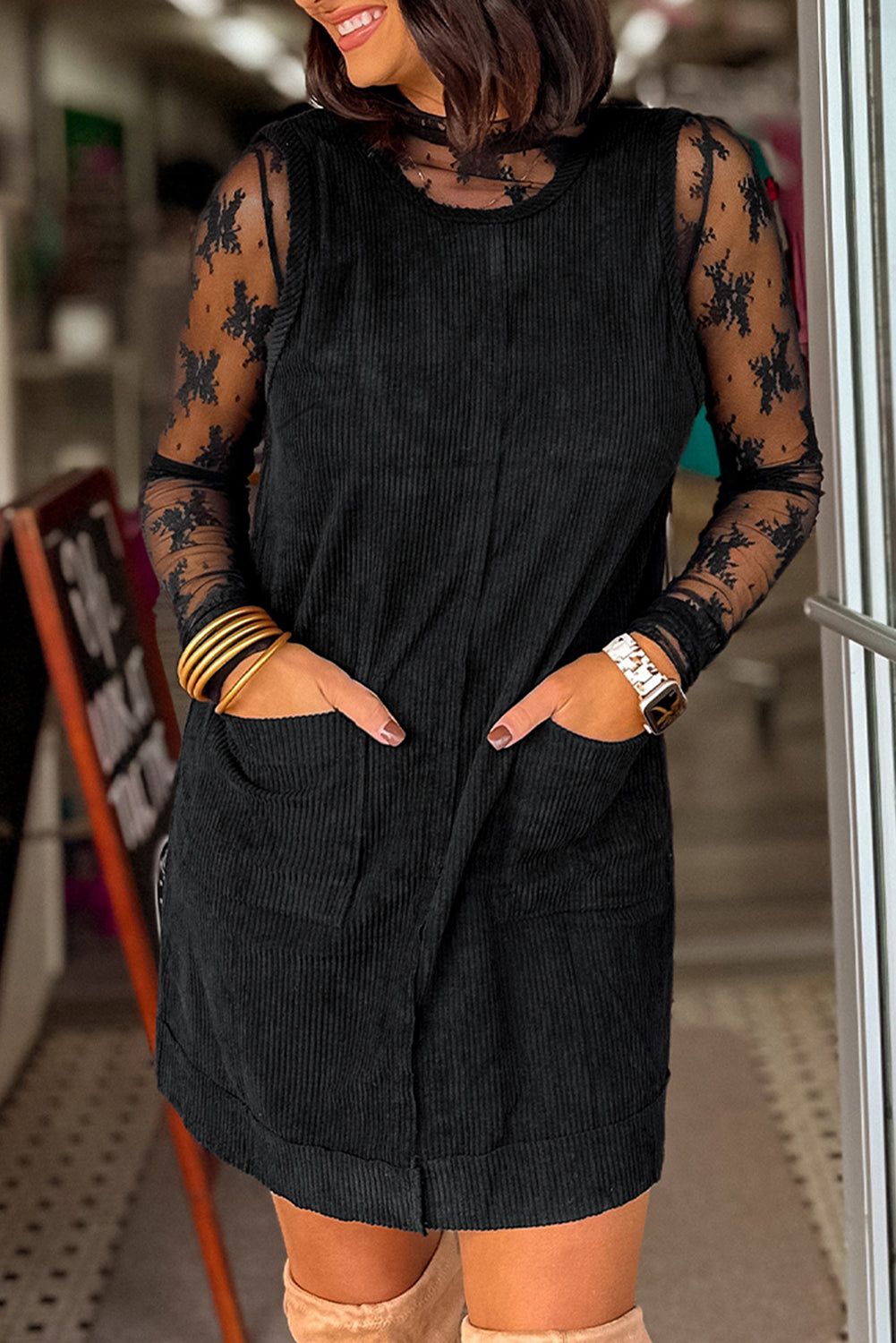 Woman wearing a black dress with sheer sleeves in an indoor setting