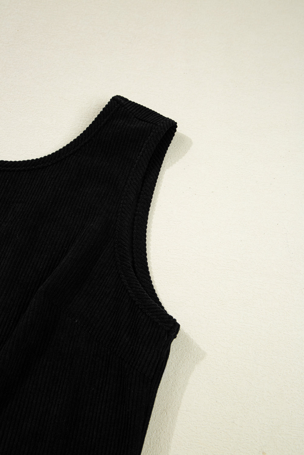 Black sleeveless top on a light beige background