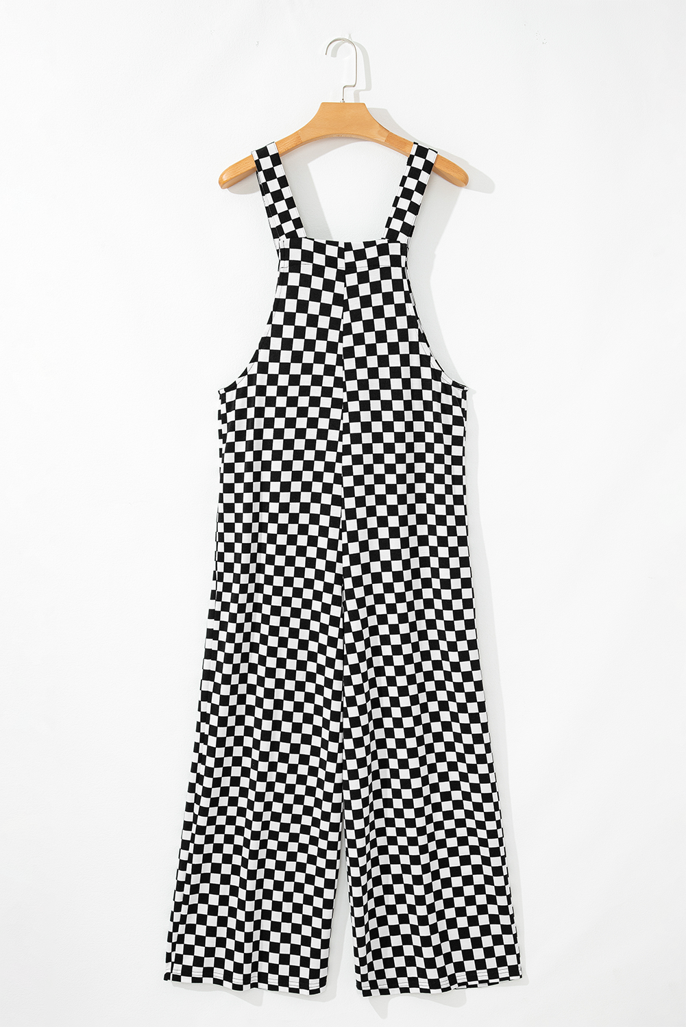 Black and white checkered jumpsuit on a hanger against a white background