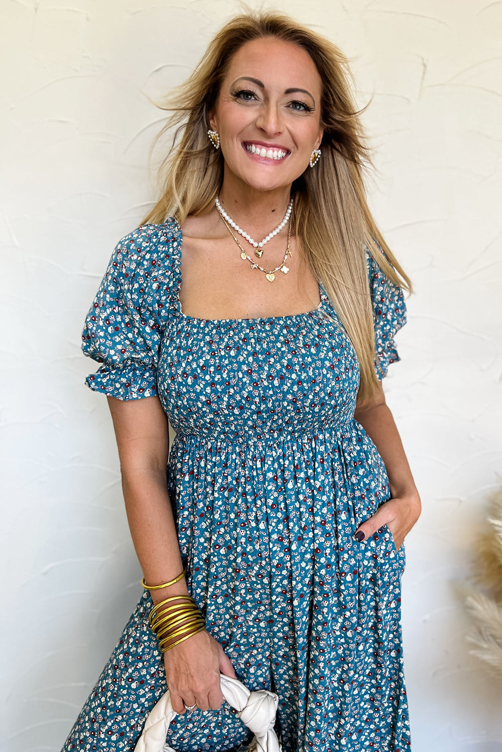 Woman wearing a blue floral dress against a white wall