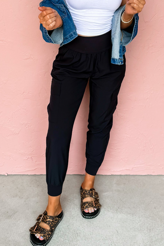 Person wearing black pants, white top, denim jacket, and leopard print sandals against a pink background
