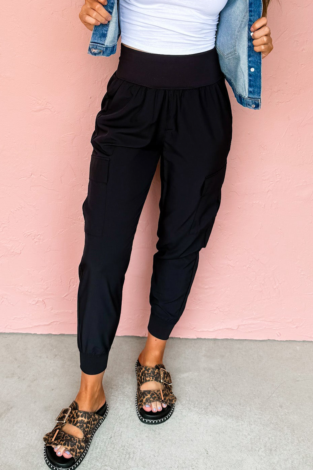 Person wearing black high-waisted pants with a light pink background