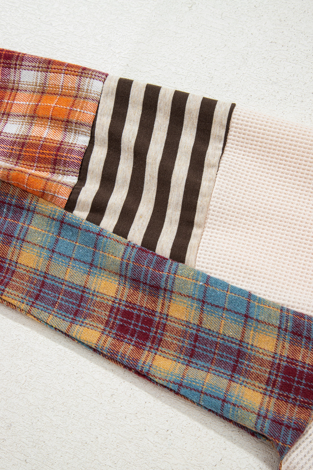 Close-up of fabric with plaid and striped patterns on a textured surface