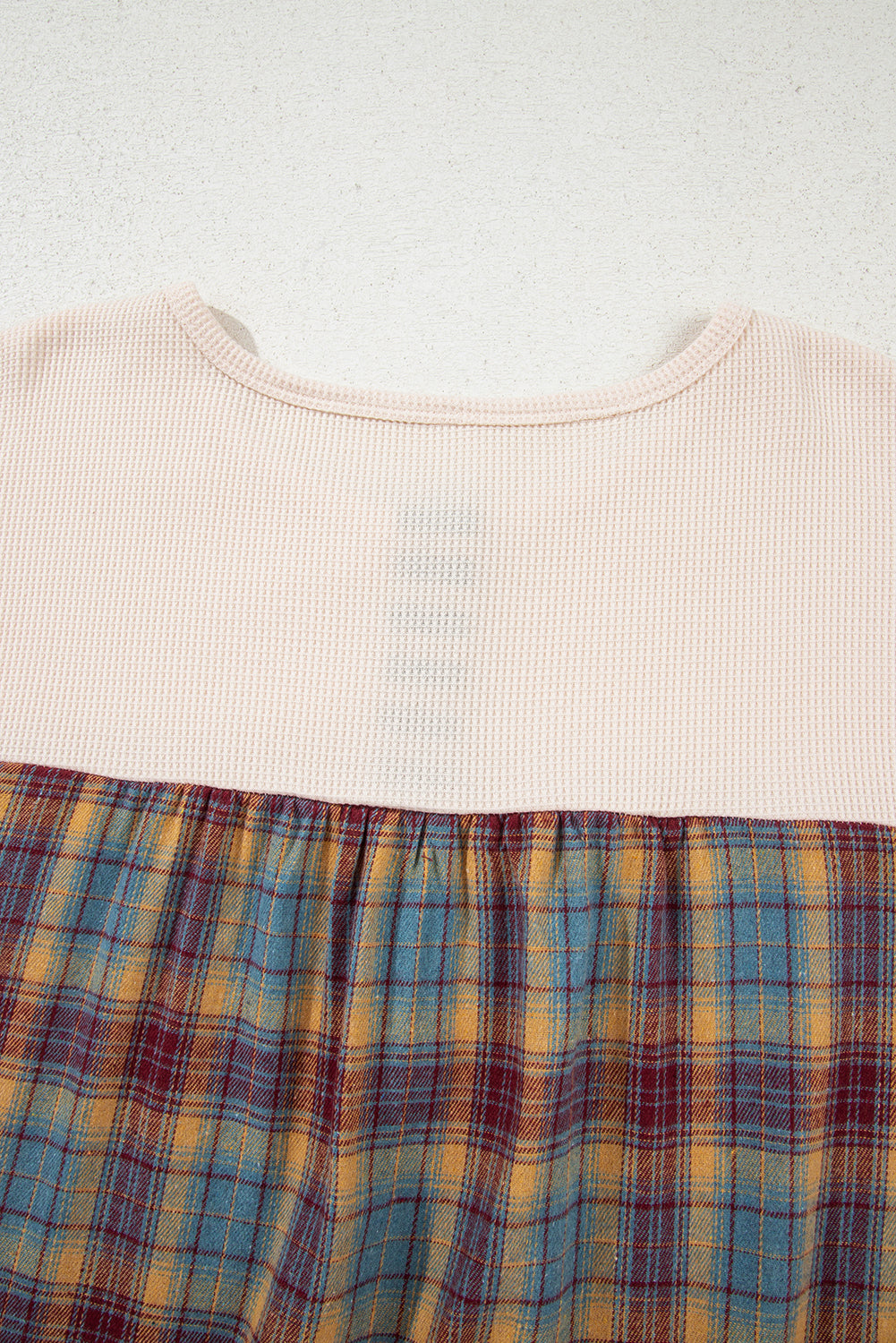 Close-up of a garment with a plaid pattern on a plain background